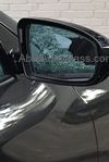 A passenger side door glass mirror on a black car. 
There is is a reflection of the broken glass on the mirror reflecting from the door glass.