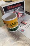 A Oswego School of Business coffe cup sitting ontop of a AGRR Magazine July August 2019 
issue with a Equalizer Rain Sensor Level Part number RSK330 in the back ground.